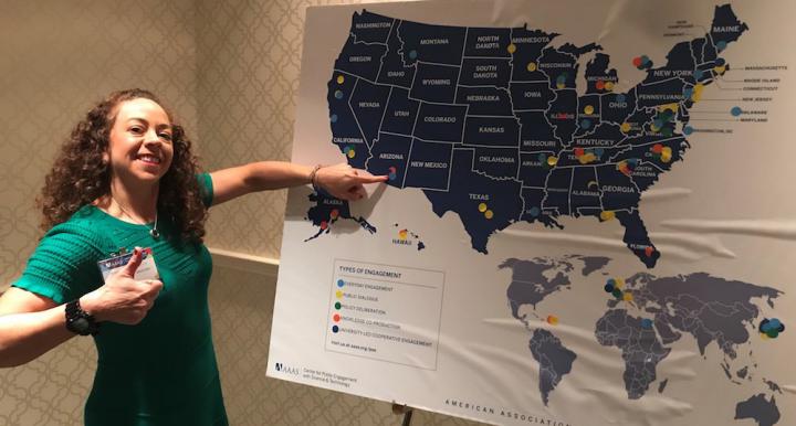 Dr. Mónica Ramírez-Andreotta pointing to Arizona on a map of the United States showing where different types of public engagement with science occur at the 185th AAAS Annual Meeting in Washington, D.C.  