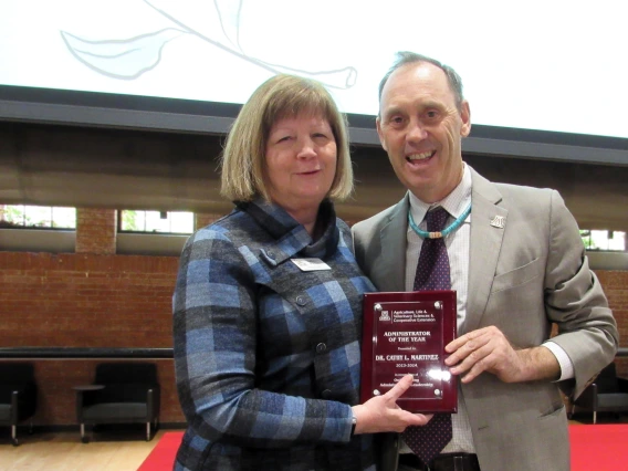 Award recipient pictured on stage with plaque, standing next to award presenter.