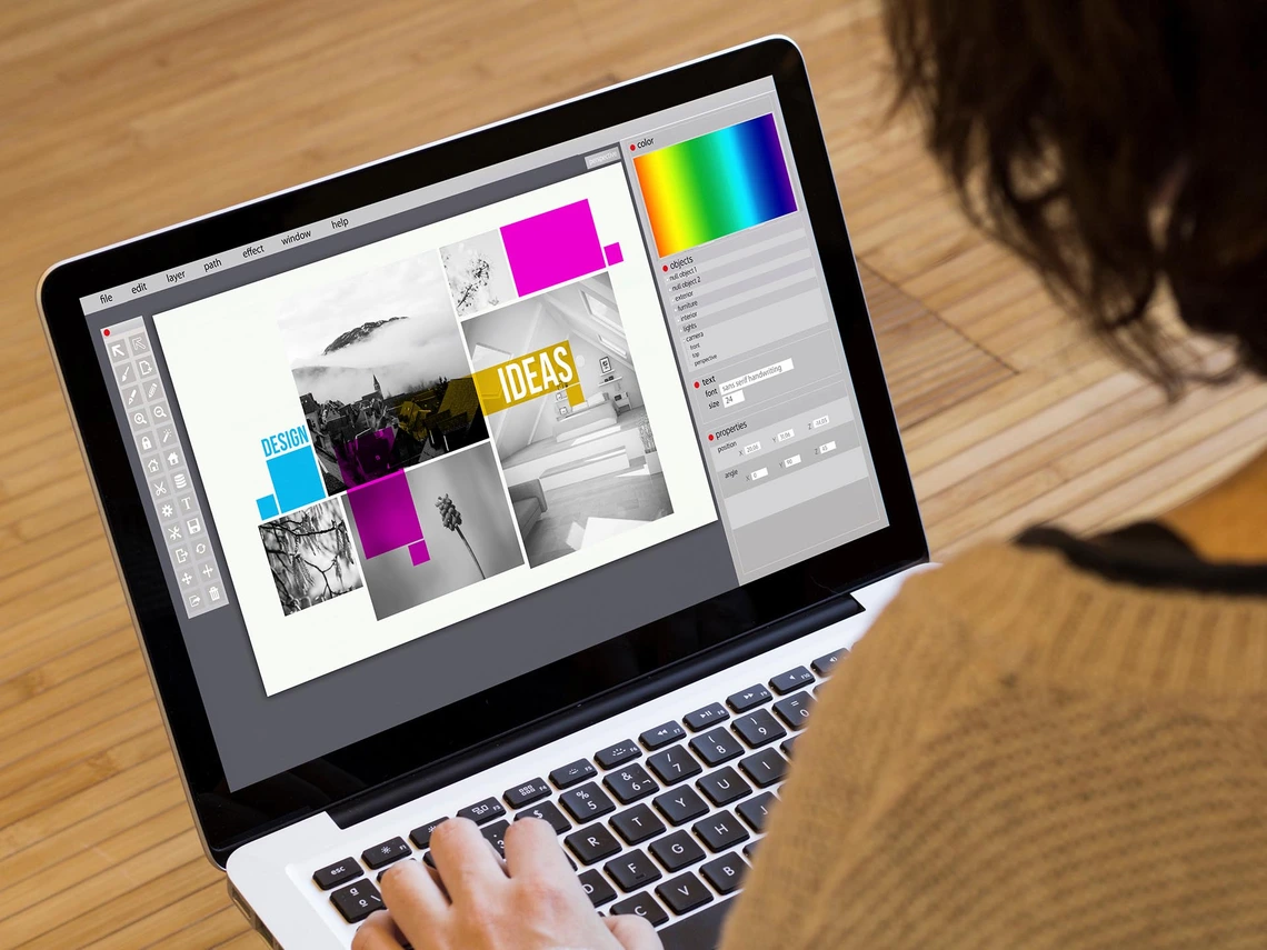 A person works on a laptop displaying a digital design layout with images, color panels, and typography arranged in a grid.