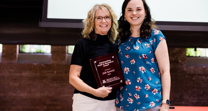 Staff member holding plaque and standing next to award presenter